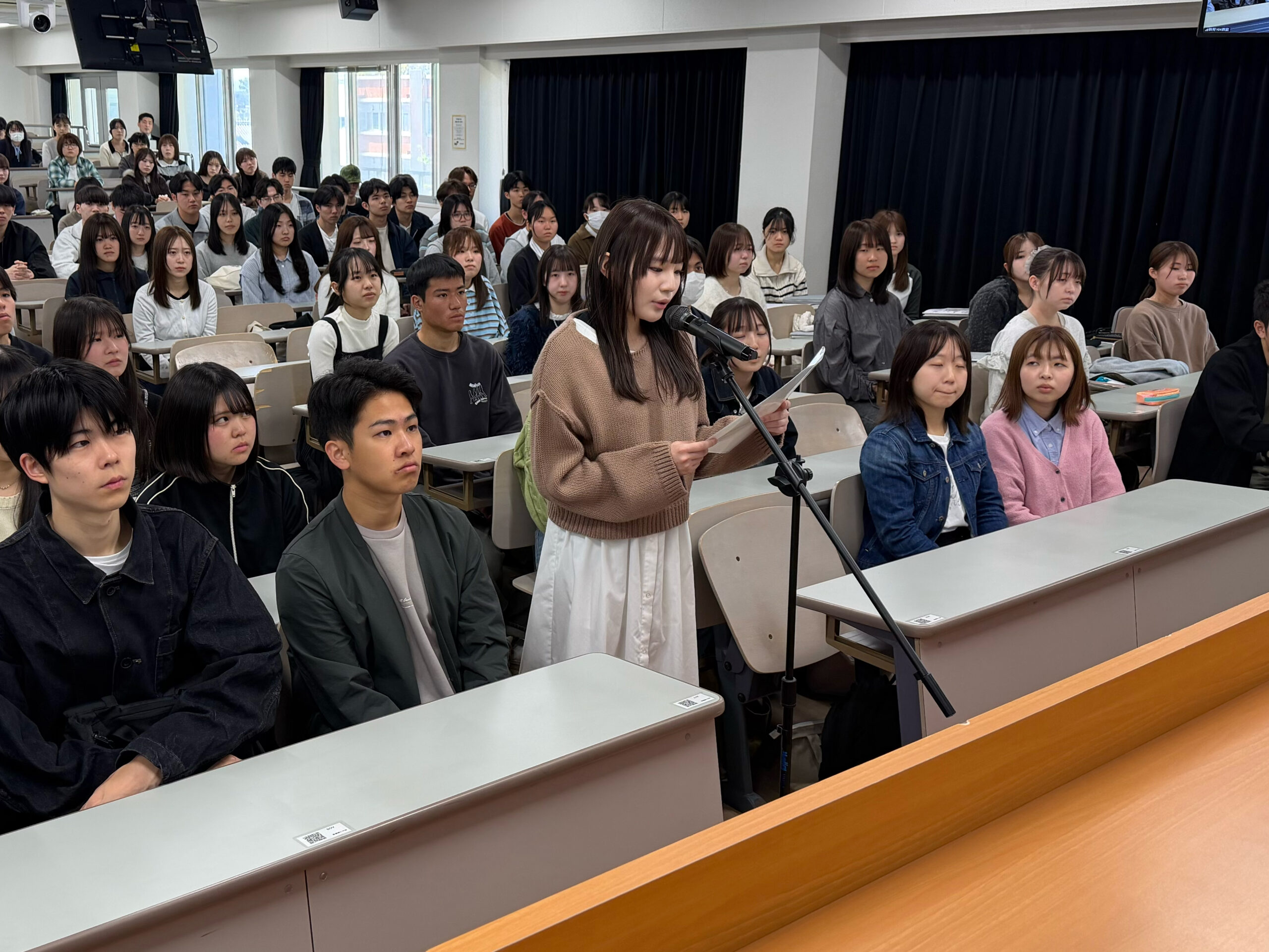 学生席の中央マイクから決意の言葉を述べる学生代表